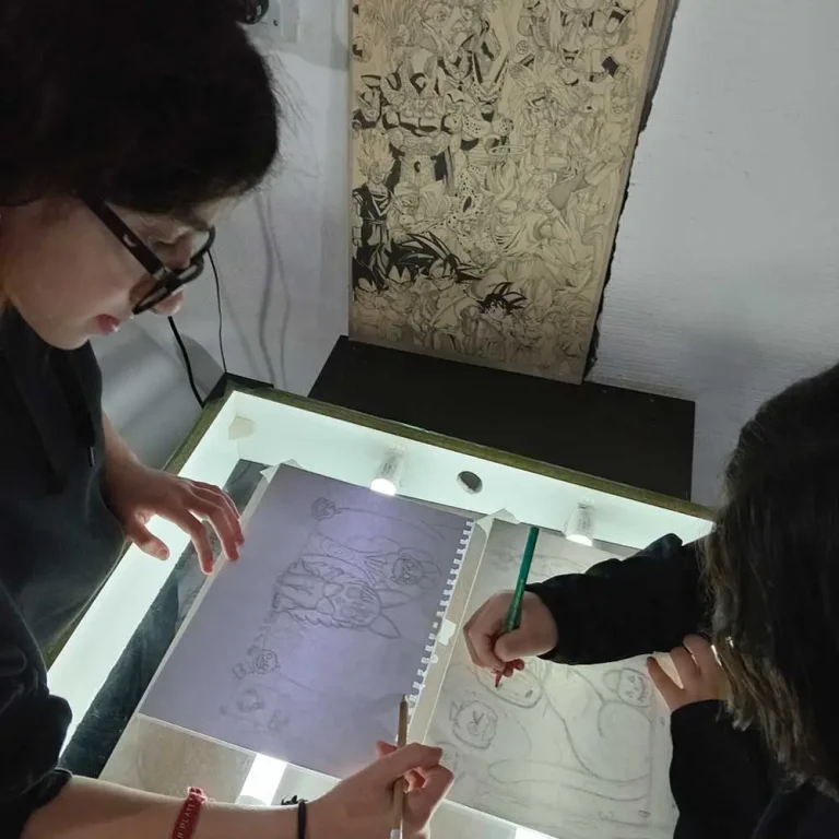 Dos alumnas dibujando manga con el tablero de luz en el primer taller temático de Zona Oeste, garantizando el método personalizado